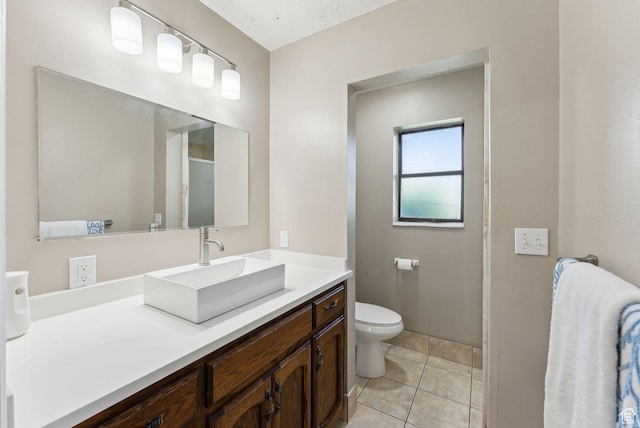 bathroom with toilet, vanity, and tile patterned floors