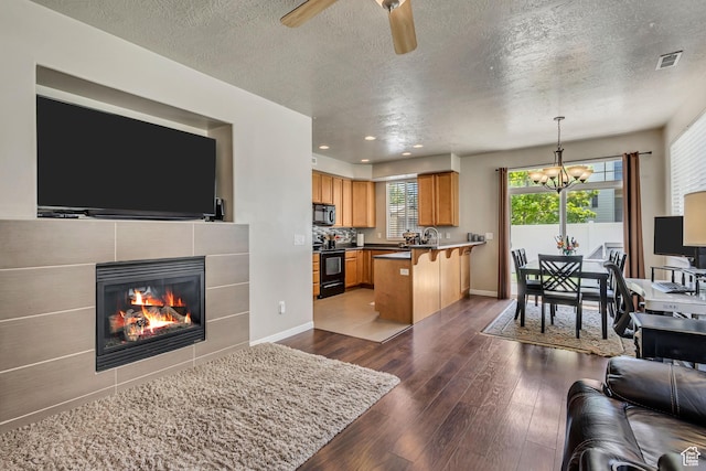6297 W Traveler Ln, West Jordan, UT 84081 - living area featuring a chandelier, dark wood-style floors, a textured ceiling, a fireplace, and a ceiling fan