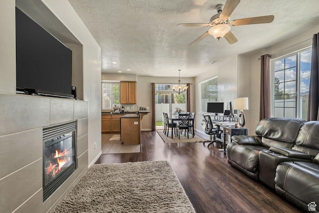 6297 W Traveler Ln, West Jordan, UT 84081 - living room with a textured ceiling, a tile fireplace, healthy amount of natural light, dark wood-style floors, and a ceiling fan