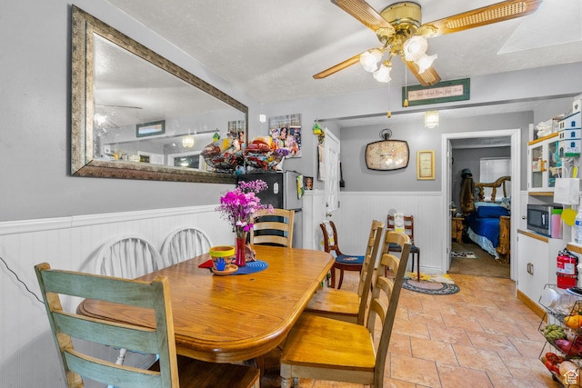 7472 S Silver Cir, West Jordan, UT 84084 - dining room with a ceiling fan, a wainscoted wall, and stone tile floors