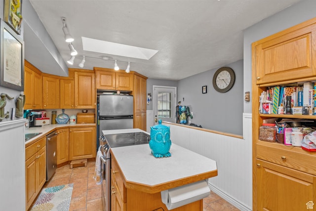 7472 S Silver Cir, West Jordan, UT 84084 - kitchen with a skylight, stainless steel appliances, a center island, light countertops, and wainscoting