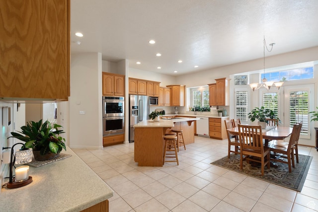 kitchen featuring stainless steel appliances, a kitchen breakfast bar, light countertops, a center island, and a chandelier