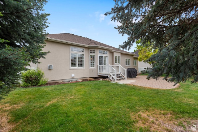back of property with stucco siding, a lawn, and a patio area