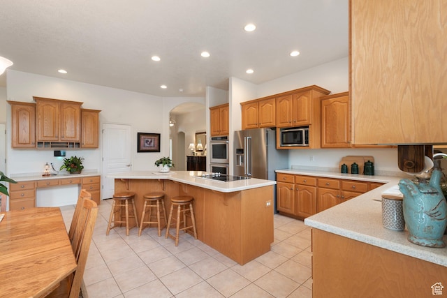 kitchen with stainless steel appliances, arched walkways, a center island, a kitchen breakfast bar, and recessed lighting