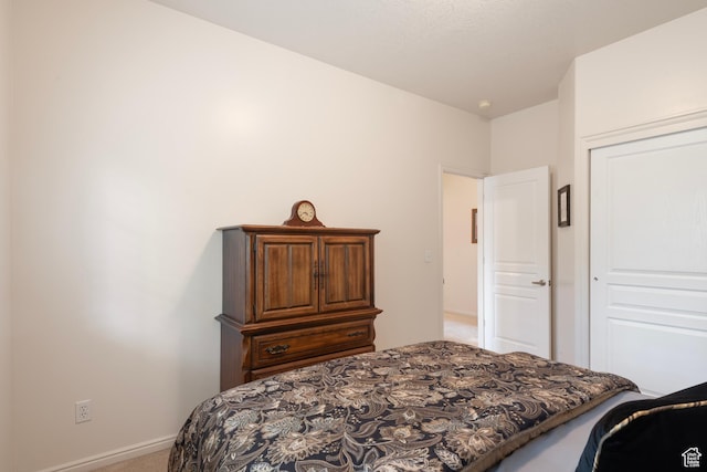 carpeted bedroom featuring baseboards and a closet
