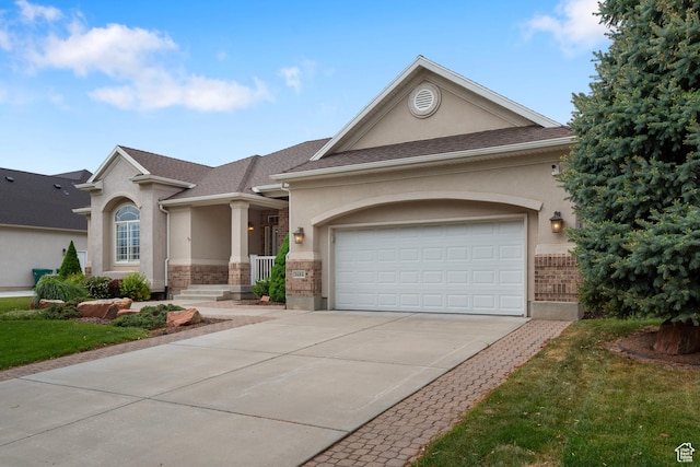 view of front of property featuring stucco siding, driveway, an attached garage, and brick siding