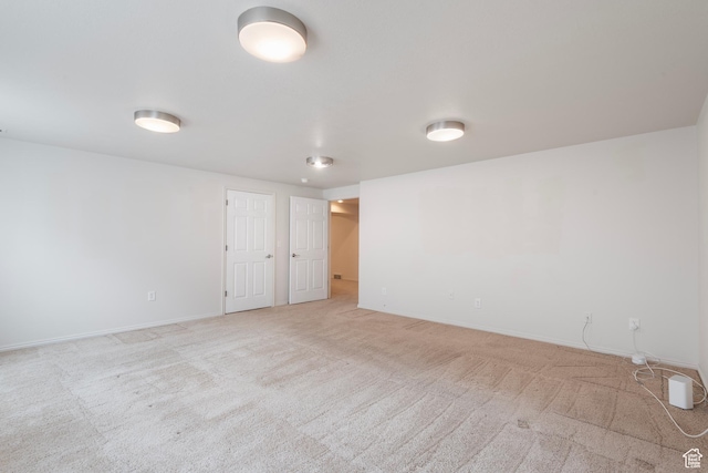 spare room featuring light carpet and baseboards