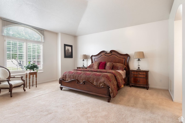 bedroom featuring carpet floors, baseboards, arched walkways, and vaulted ceiling