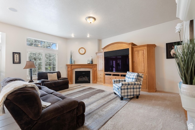 living room with a tiled fireplace, light colored carpet, and baseboards