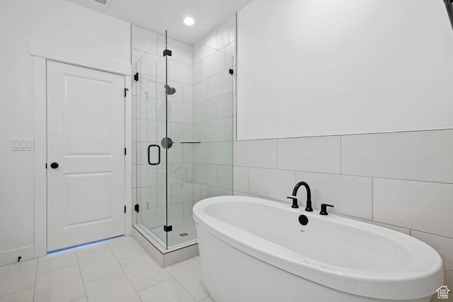 full bath featuring a shower stall, tile walls, a freestanding bath, and tile patterned flooring