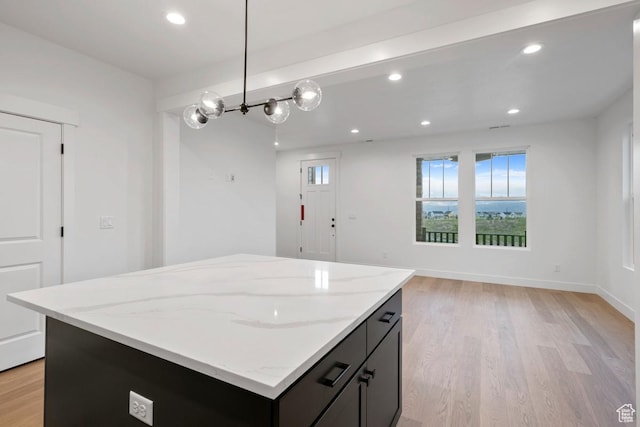 kitchen featuring light wood-style flooring, a center island, light stone countertops, recessed lighting, and hanging light fixtures