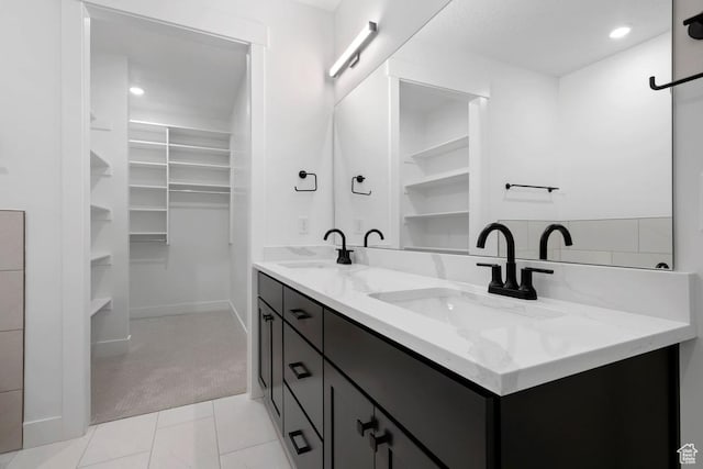 bathroom featuring a spacious closet, double vanity, and recessed lighting