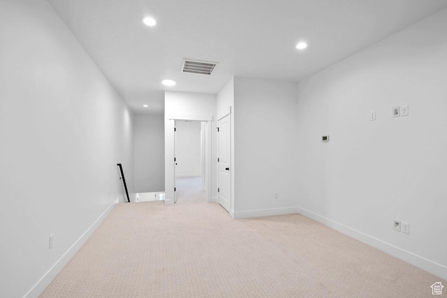 spare room featuring recessed lighting, light colored carpet, and baseboards