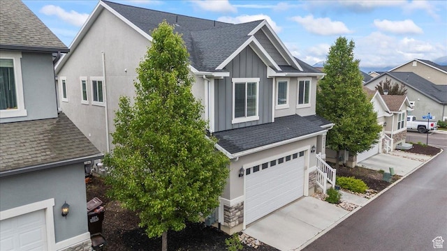 view of front of home with board and batten siding, a garage, a shingled roof, and concrete driveway