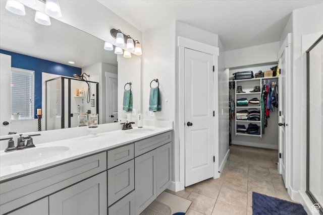 bathroom featuring a shower stall, double vanity, tile patterned flooring, and a walk in closet