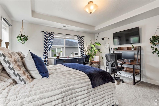 bedroom with carpet floors, multiple windows, a desk, and a raised ceiling