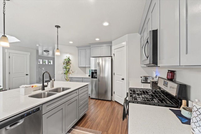 kitchen featuring stainless steel appliances, a sink, hanging light fixtures, gray cabinets, and recessed lighting