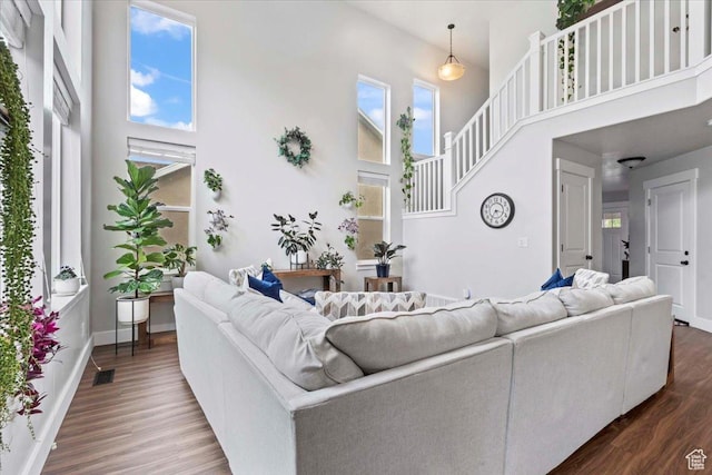 living area with a towering ceiling, dark wood-style floors, baseboards, and stairway