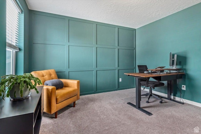 carpeted home office featuring a decorative wall and a textured ceiling