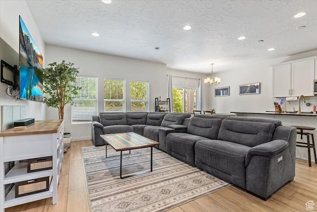 living area featuring a chandelier, recessed lighting, light wood-style floors, and a textured ceiling