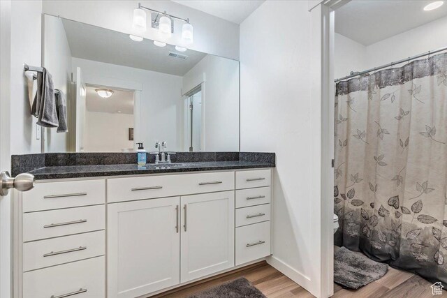 bathroom with wood finished floors, toilet, vanity, and baseboards