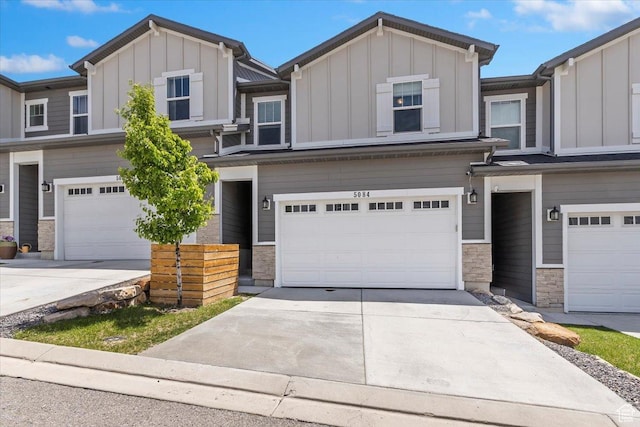 view of front of property featuring board and batten siding, an attached garage, stone siding, and concrete driveway