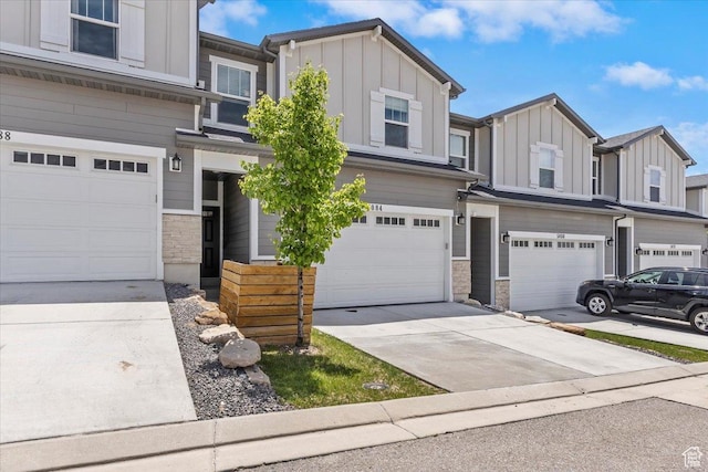 multi unit property with board and batten siding, a garage, stone siding, and concrete driveway