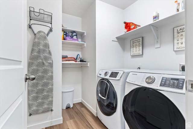 laundry room with washing machine and dryer, wood finished floors, and baseboards