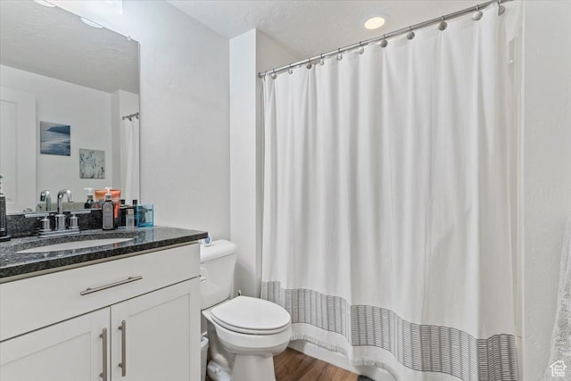 full bath with toilet, vanity, and wood finished floors