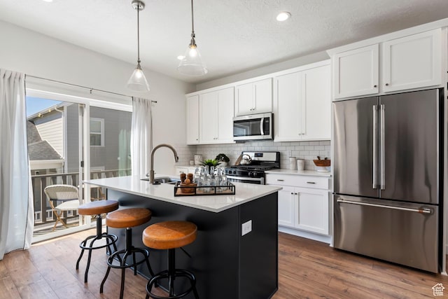 kitchen with appliances with stainless steel finishes, a sink, a kitchen island with sink, white cabinetry, and recessed lighting