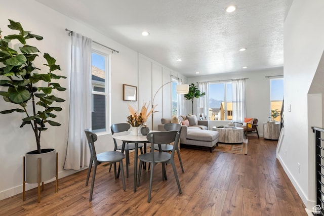 dining space featuring wood-type flooring, recessed lighting, plenty of natural light, baseboards, and a textured ceiling