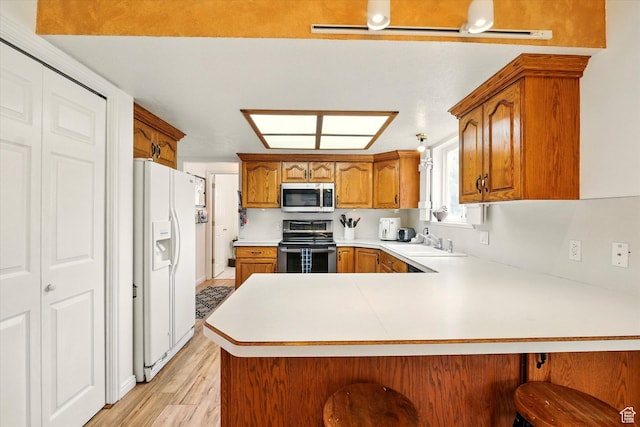 211 S 300 E, Wellsville, UT 84339 - kitchen with stainless steel appliances, a peninsula, a sink, brown cabinetry, and light countertops