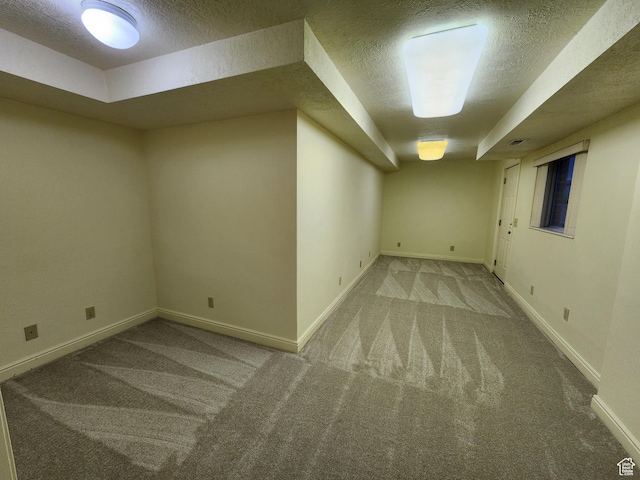 finished below grade area with a textured ceiling, carpet flooring, and baseboards