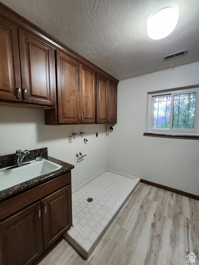 laundry room featuring cabinet space, washer hookup, light wood-style floors, baseboards, and a textured ceiling