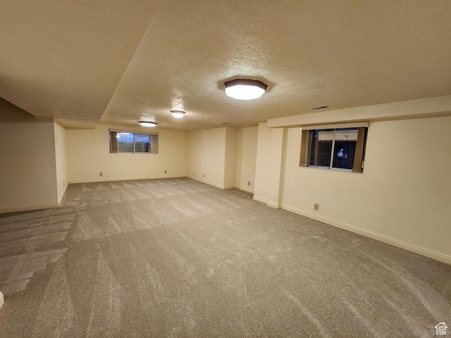 finished below grade area with carpet, a textured ceiling, and baseboards