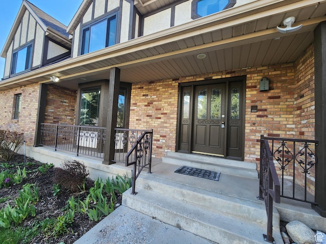 doorway to property featuring a porch and brick siding