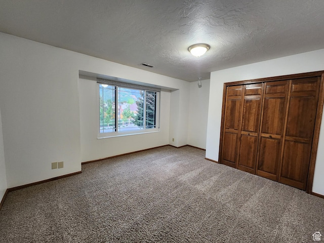 unfurnished bedroom featuring carpet, baseboards, a textured ceiling, and a closet
