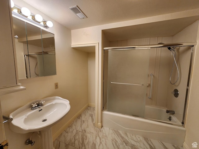 bathroom with marble look tile flooring, a sink, combined bath / shower with glass door, and baseboards