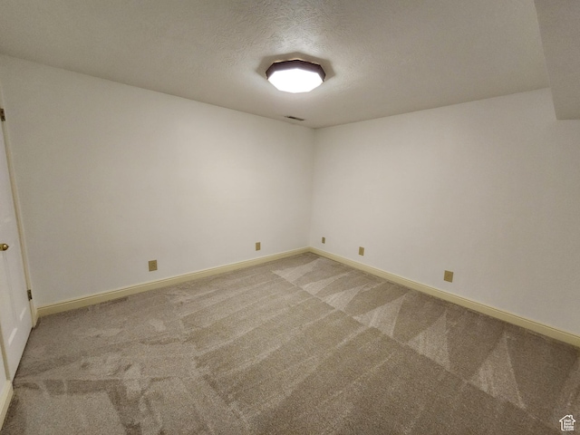 unfurnished room featuring light colored carpet, a textured ceiling, and baseboards