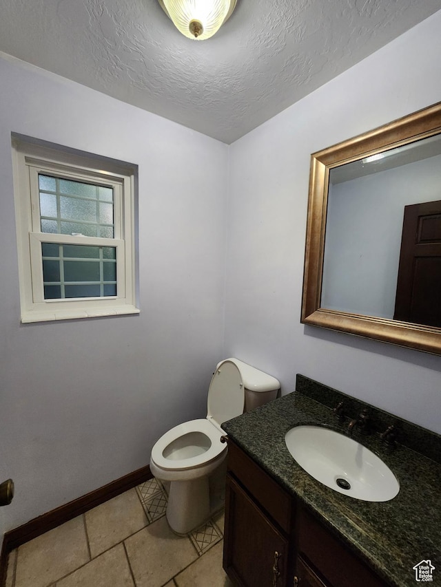 bathroom featuring toilet, baseboards, vanity, and a textured ceiling