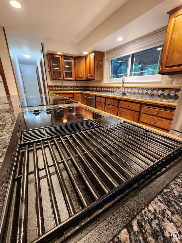 kitchen featuring a sink, brown cabinetry, recessed lighting, dark countertops, and backsplash