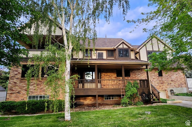 view of front facade featuring a front lawn, brick siding, stairway, and stucco siding