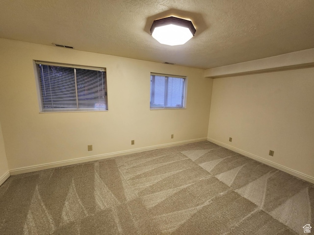 carpeted spare room with a textured ceiling and baseboards