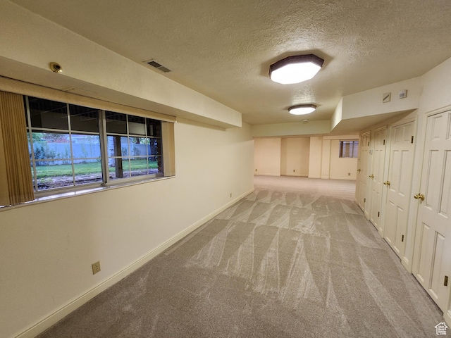 carpeted spare room with a textured ceiling and baseboards