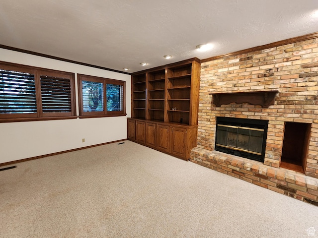 unfurnished living room with carpet floors, baseboards, a fireplace, crown molding, and built in shelves