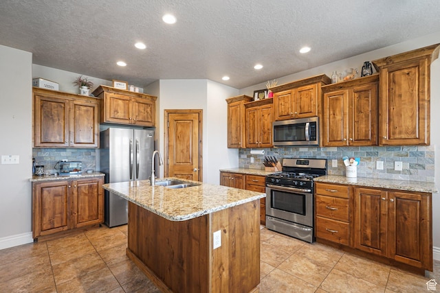 607 N 1980 E Unit 139, Spanish Fork, UT 84660 - kitchen with appliances with stainless steel finishes, a sink, brown cabinetry, backsplash, and a center island with sink