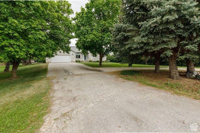 540 N 100 E, Hyde Park, UT 84318 - view of property hidden behind natural elements featuring concrete driveway, a front lawn, stone siding, and an attached garage