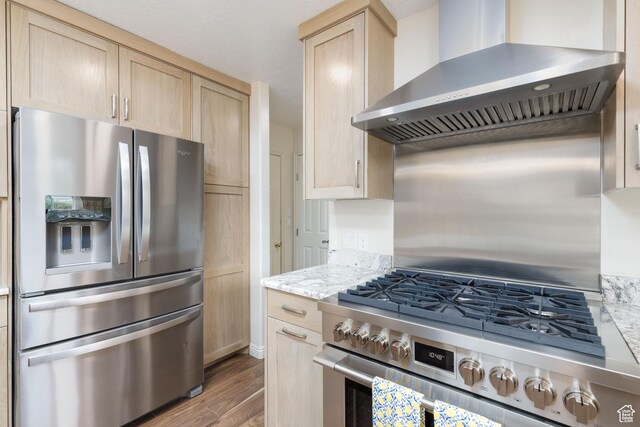 540 N 100 E, Hyde Park, UT 84318 - kitchen featuring stainless steel appliances, wall chimney exhaust hood, light brown cabinetry, wood finished floors, and light stone counters