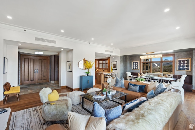 living area with wood finished floors, baseboards, recessed lighting, and crown molding