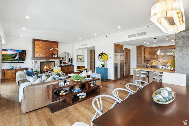 living room featuring wood finished floors, crown molding, recessed lighting, and a fireplace